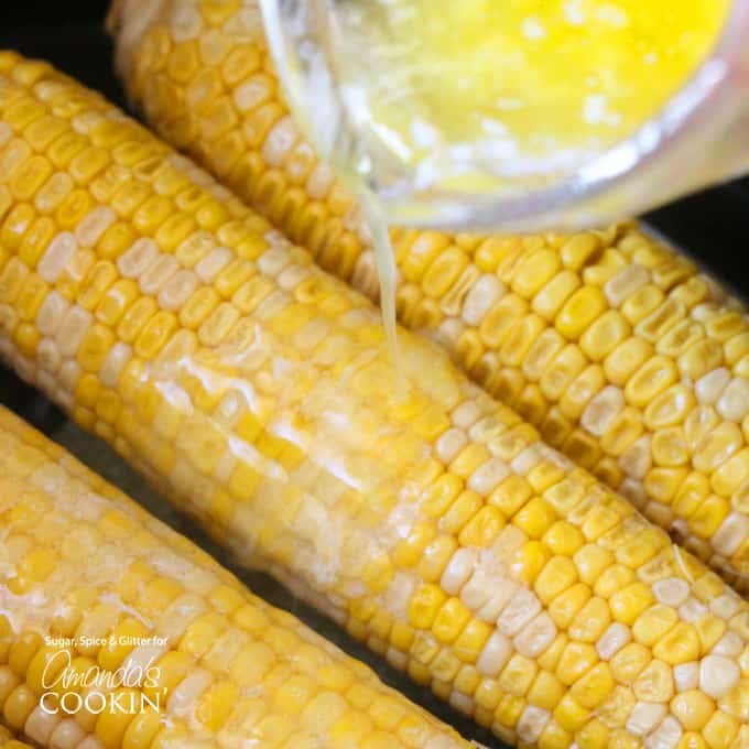 An overhead of melted butter being poured over corn.