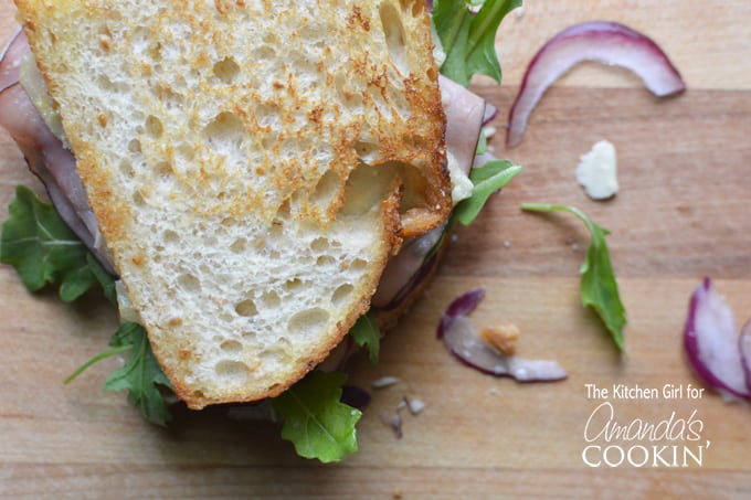 An overhead close up of a toasted cheddar, ham and arugula sandwich.