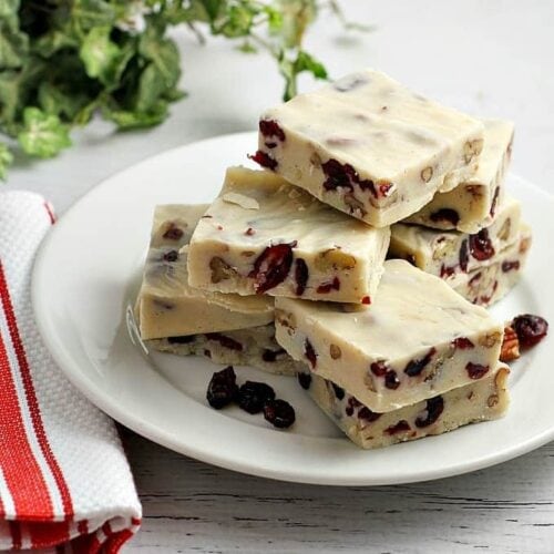 Squares of white chocolate cranberry fudge on a white plate.