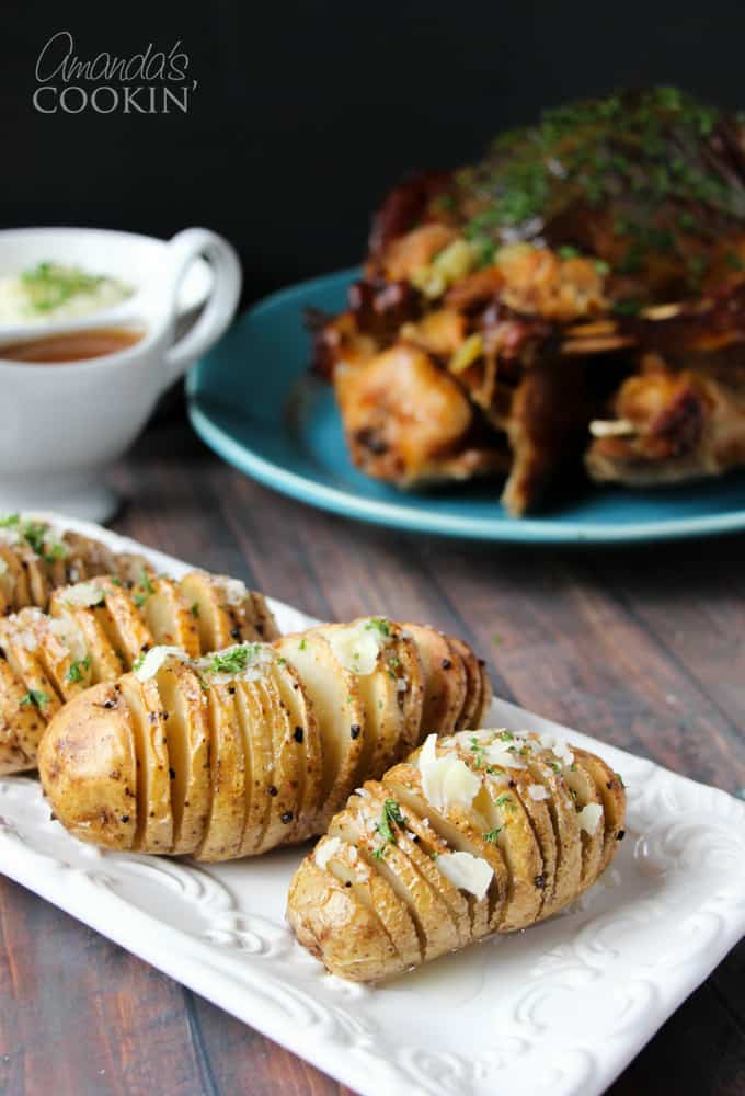 Hasselback potatoes resting on a rectangular white plate.