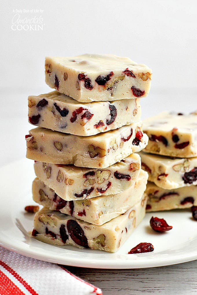Squares of white chocolate cranberry fudge stacked on top of each other.