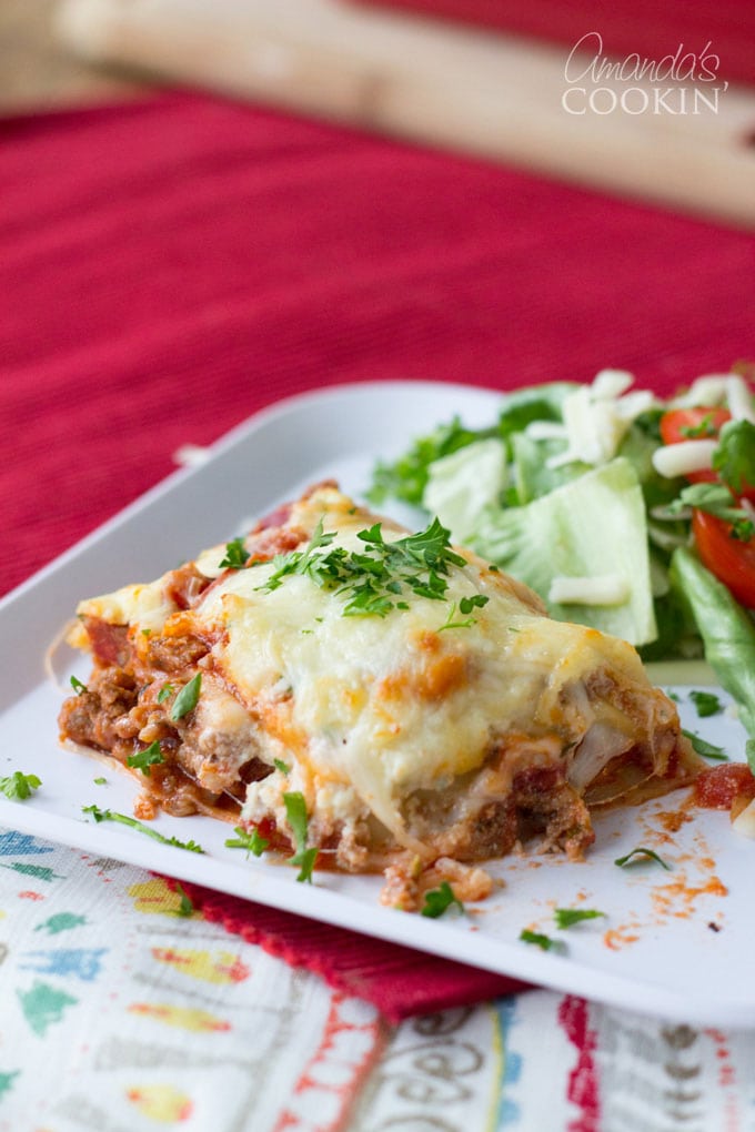 slice of lasagna on a plate with salad