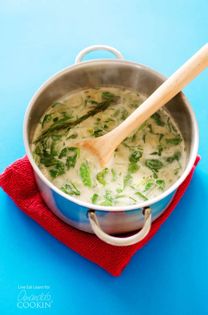 A pot of white bean soup with a wooden spoon resting inside it.