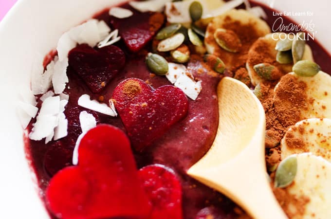 A close up of a wooden spoon in a bowl of red velvet smoothie.