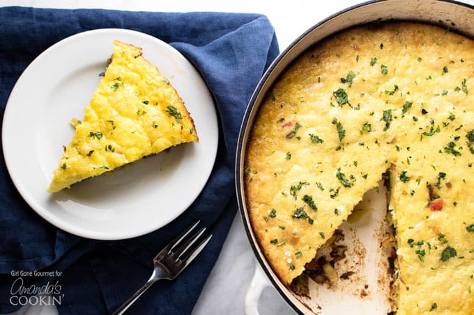 A slice of vegetable frittata on a white plate next to the pan of frittata.