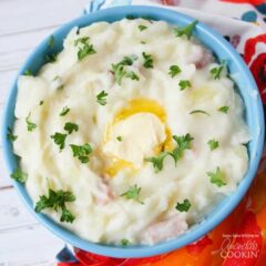 A bowl of colcannon mashed potatoes topped with chopped parsley and melted butter.