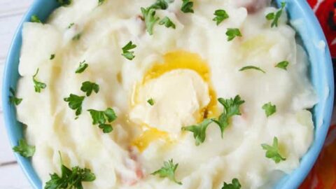 A bowl of colcannon mashed potatoes topped with chopped parsley and melted butter.