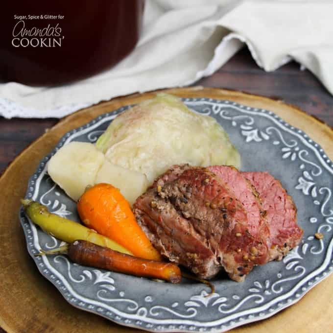 A blue plate with cooked corned beef, cabbage and carrots.