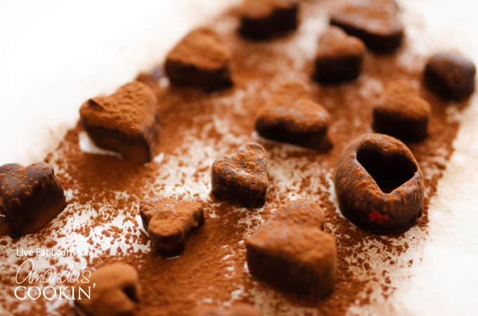 A close up of chocolate covered fruit truffles freshly sprinkled with cocoa powder.