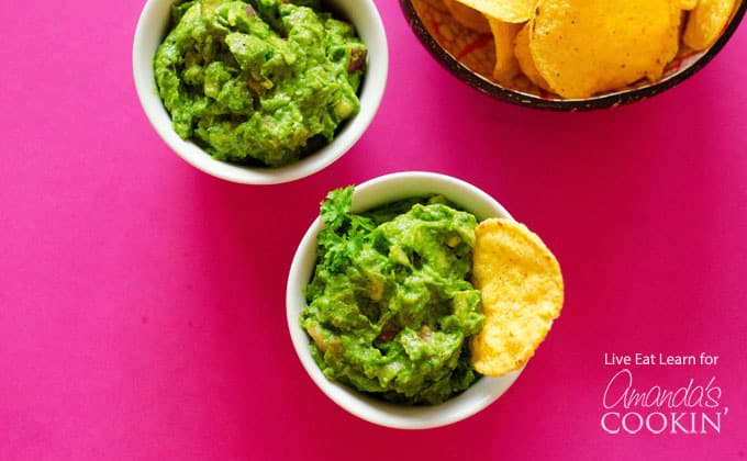 An overhead picture of two white bowls filled with guacamole.