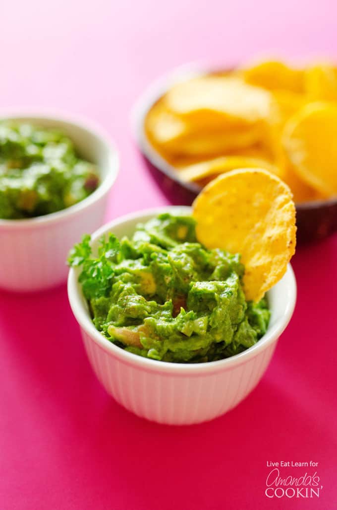 A bowl of guacamole with a tortilla dipped in.