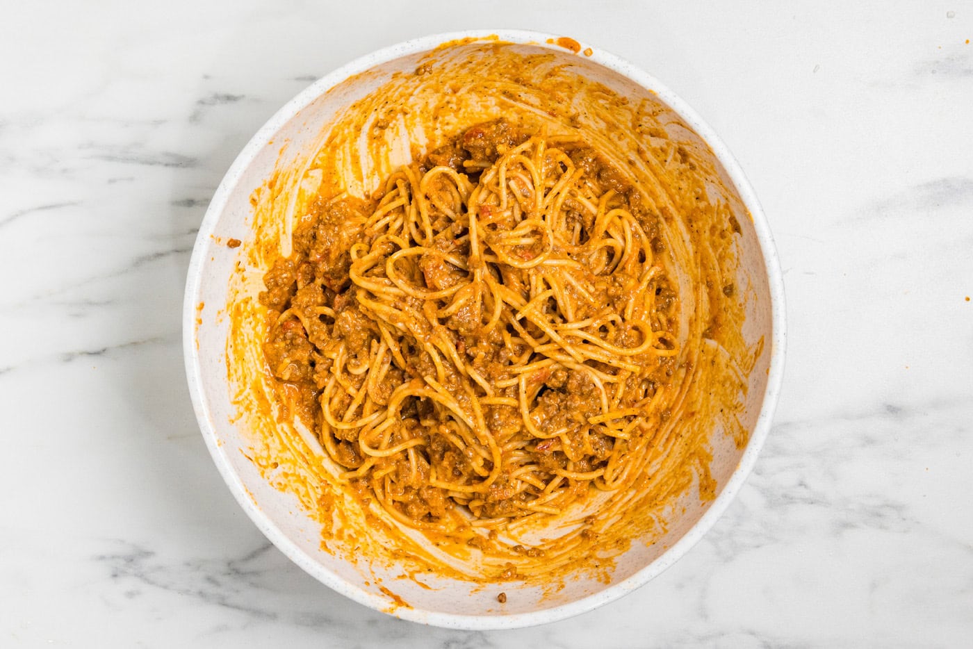 Spaghetti mixture fully combined with ricotta, egg and parmesan in a mixing bowl