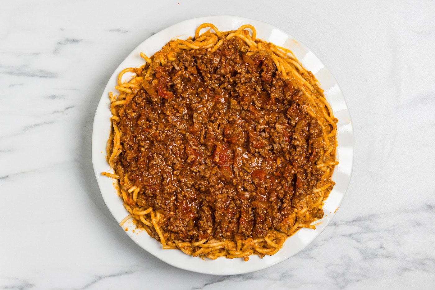 Remaining meat sauce spread over the spaghetti layer in the pie plate