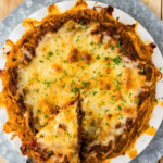 Overhead spaghetti pie with one slice cut and lifted out on a pie server