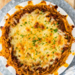 Overhead view of a baked spaghetti pie topped with melted mozzarella and parsley
