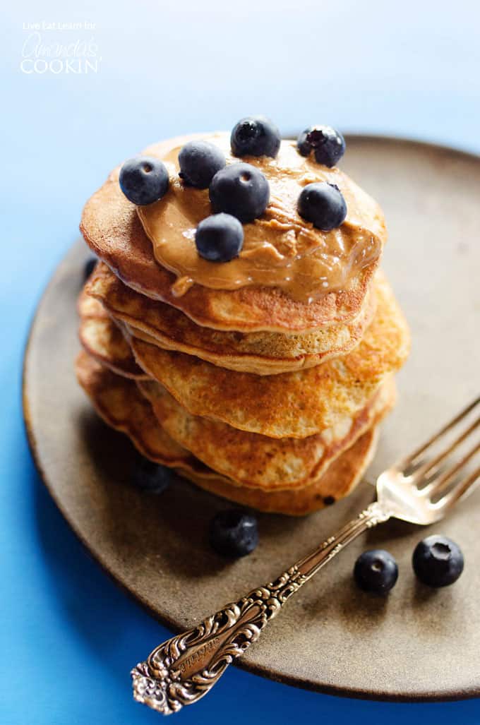 stack of pancakes with blueberries on top on a brown plate