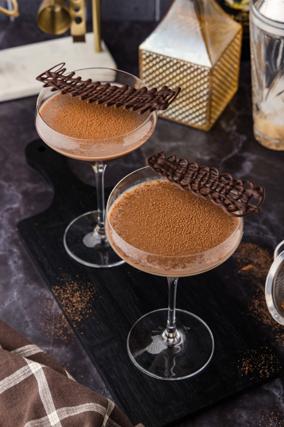 Two Baileys Chocolate Martinis topped with cocoa powder and chilled melted chocolate swirls