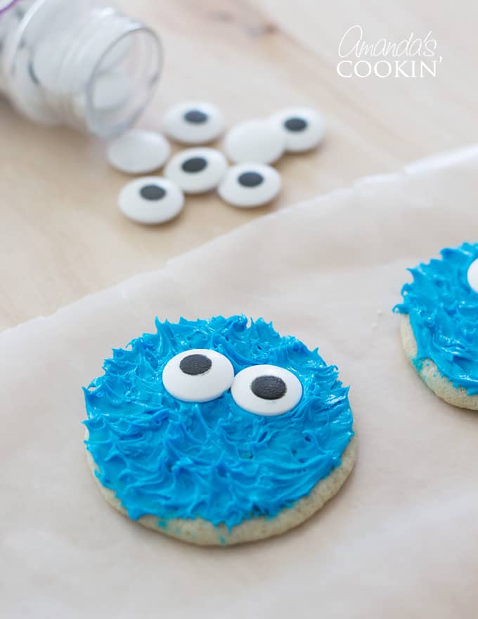 cookie monster cookie on parchment paper with candy eyes in background