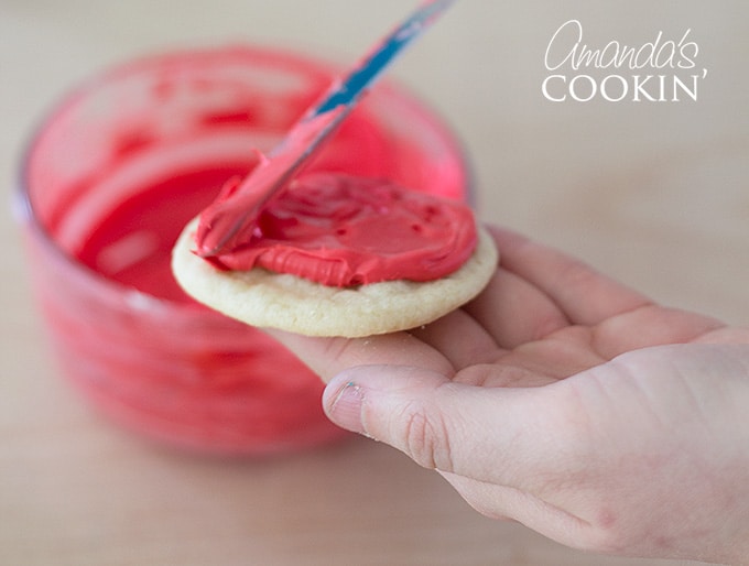 spreading red frosting on a cookie