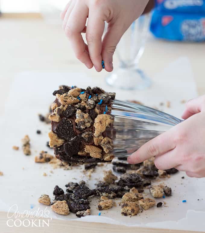 Go through and press in your cookie crumbles to make sure they stay in place. Now, take your blue sprinkles and sprinkle them over any other open-frosted spots on the glass. Piece them in and press them down slightly.