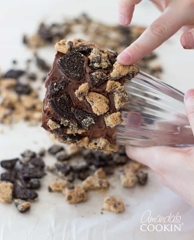 Take your freshly frosted milkshake glass and lightly roll it in the cookie crumbles. Try not to press to hard otherwise it will smear the frosting on the glass and won't stick as well. 