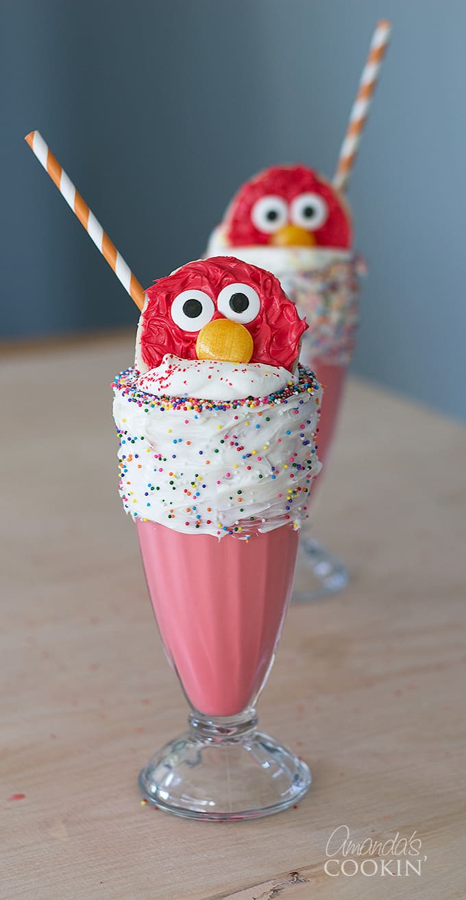 Elmo Freakshakes in a glass with vanilla frosted rim and elmo cookie.