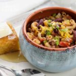 chili mac in a bowl with cornbread on the side