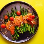 a black plate with asparagus and sauce