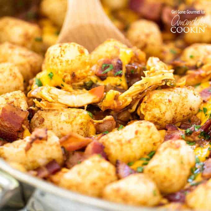 BBQ chicken, tater tots, and bacon in a skillet with wooden spoon