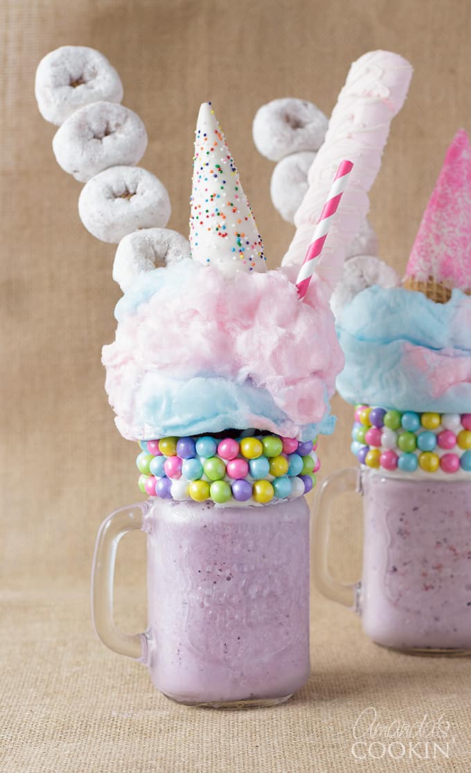 two purple milkshakes with donuts and marshmallows