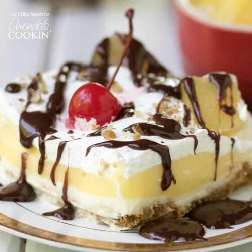 banana split layered dessert with cherry and chocolate drizzle garnish