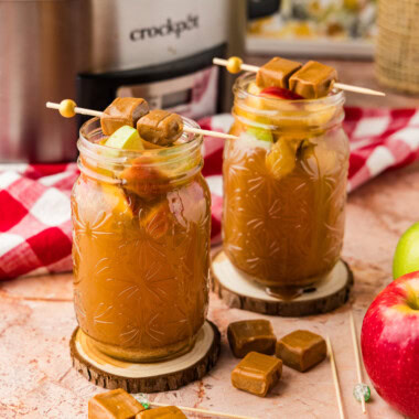 two mason jars of Crockpot Caramel Apple Cider with caramel candies