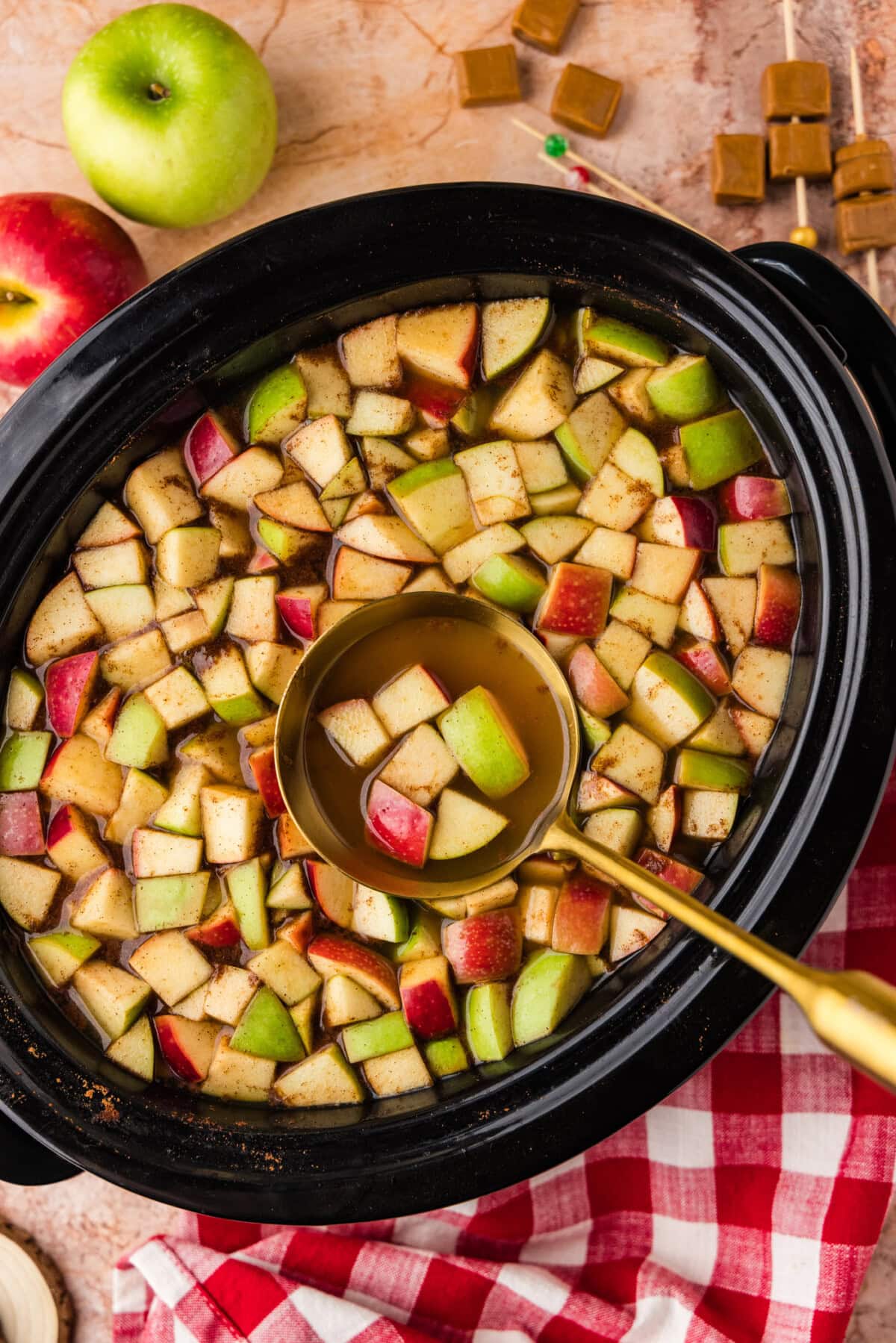 ladle of Crockpot Caramel Apple Cider with chopped apples