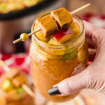 hand lifting a glass of Crockpot Caramel Apple Cider