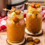 two glasses of Crockpot Caramel Apple Cider with crockpot in background