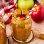 Crockpot Caramel Apple Cider in a glass garnished with caramel candy and apples and crockpot in background