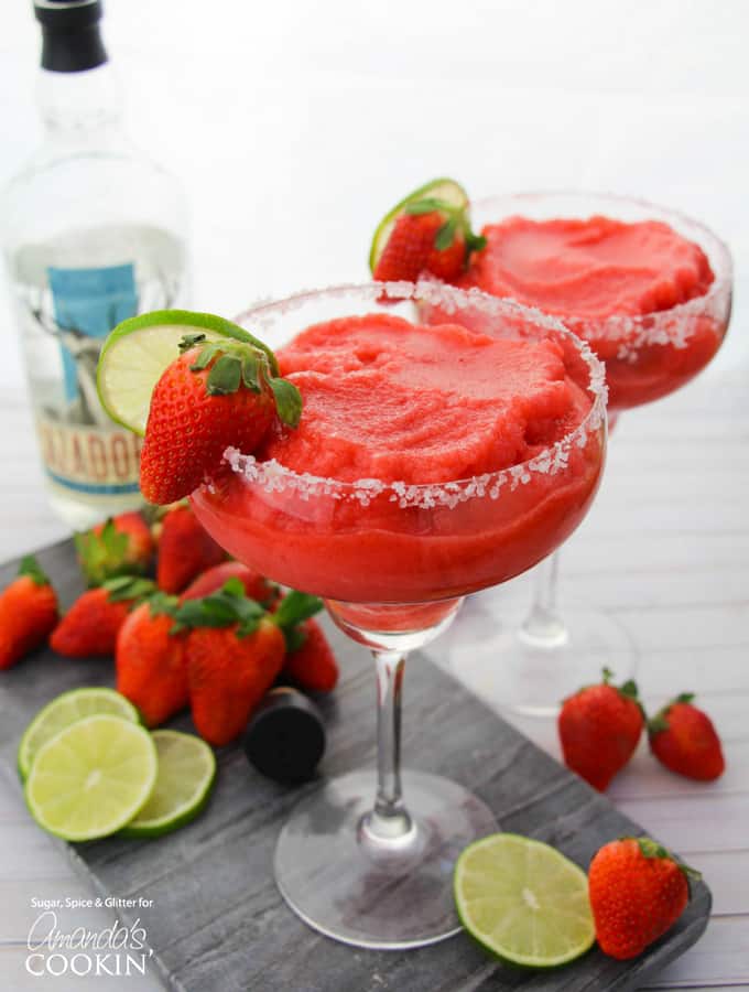 Two frozen Strawberry Margaritas with strawberry and lime garnish