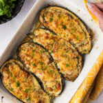 hands lifting a baking dish of stuffed baked eggplant parmesan
