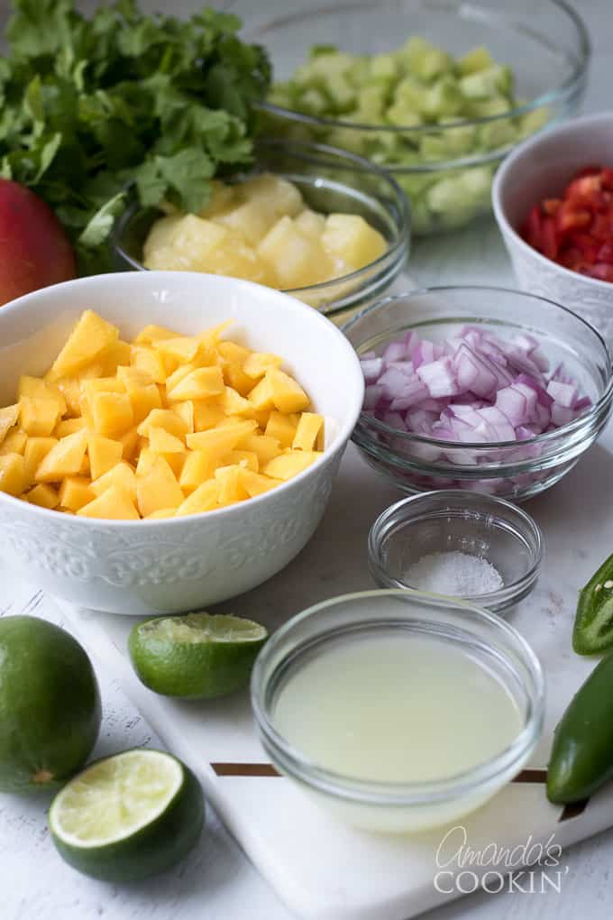 mangoes, cucumber, red bell pepper, pineapple, cilantro and jalapeno in bowls