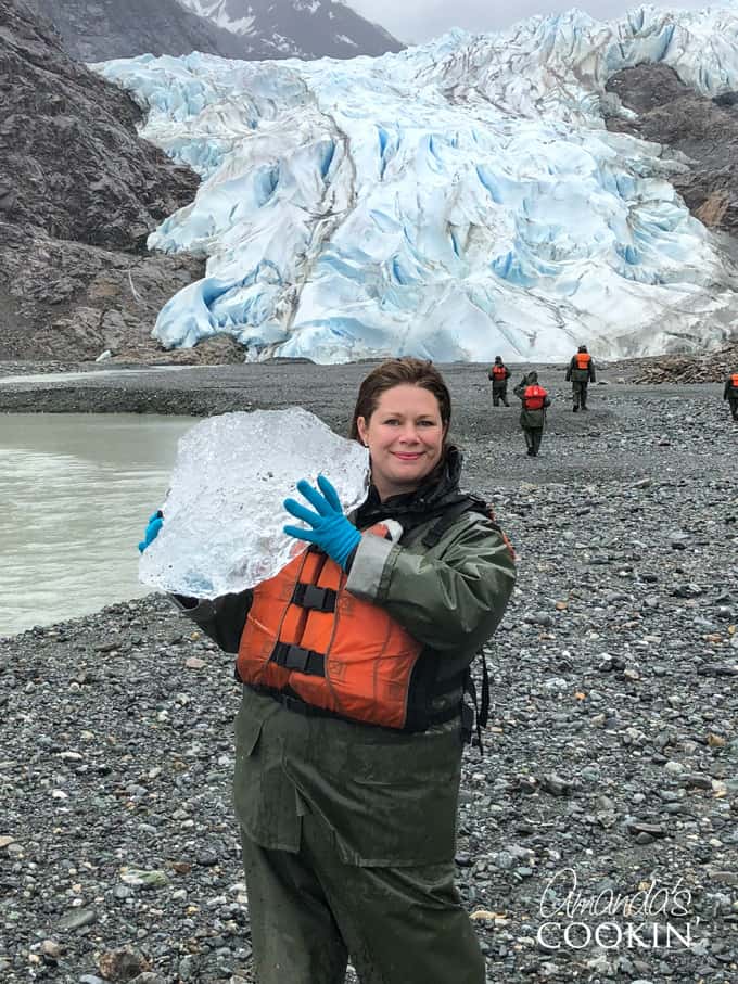 A person standing in front of a Davidson Glacier holding a big chunk of ice