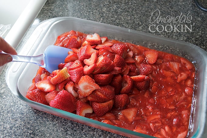 mixing fresh strawberries into strawberry sauce