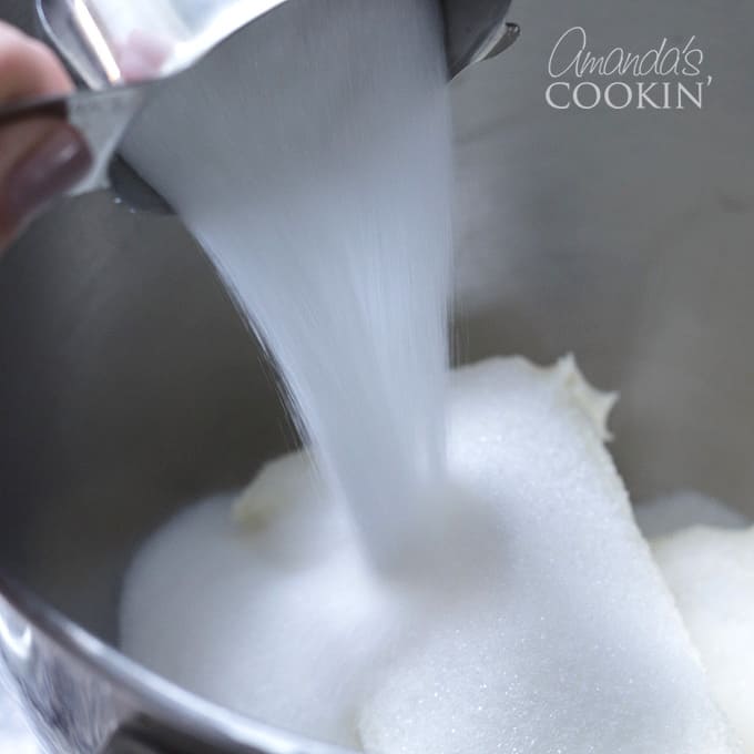 adding sugar to cream cheese in a mixer
