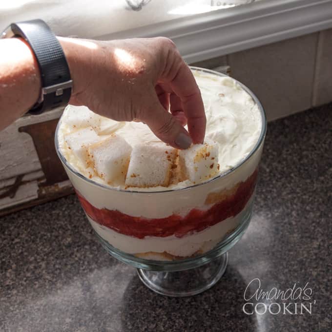 placing angel food cake cubes on top of trifle dessert