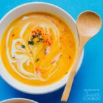 creamy cauliflower soup in a bowl with wooden spoon