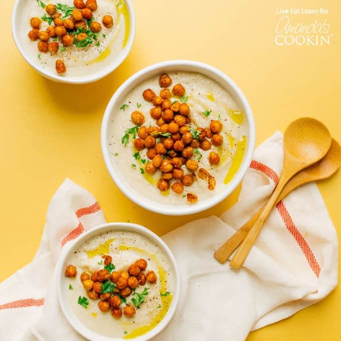 three bowls of cauliflower soup with chickpea garnish