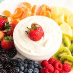 bowl of cream cheese fruit dip with fruit on a plate