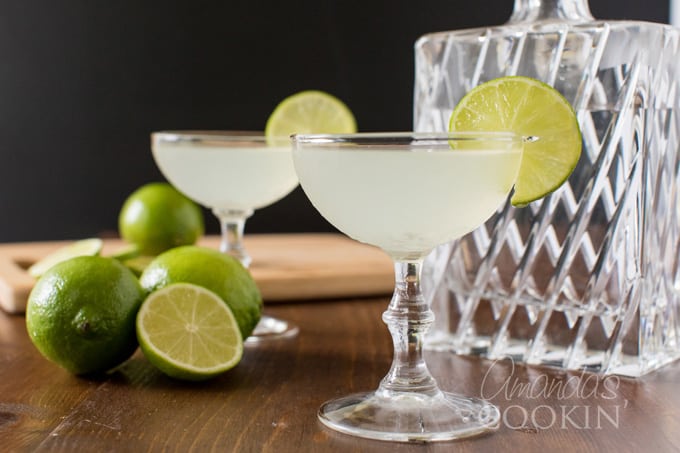 Two gimlets in coupe glasses garnished with lime wheels