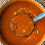 ladling out Homemade Tomato Soup with Fresh Tomatoes