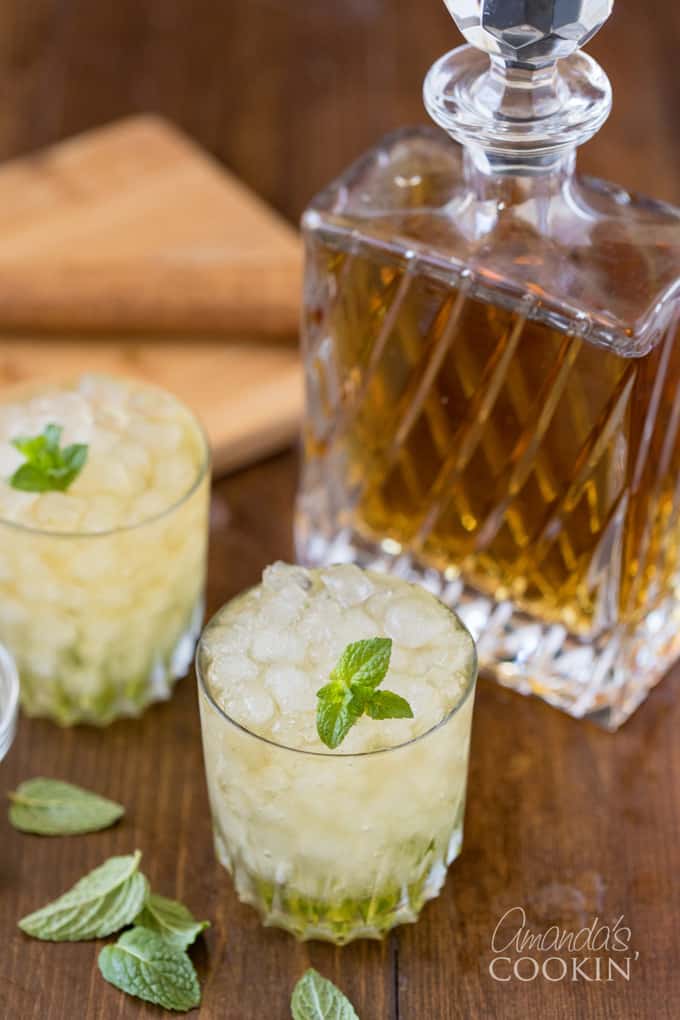 bourbon whiskey in crystal bottle with two glasses of mint julep