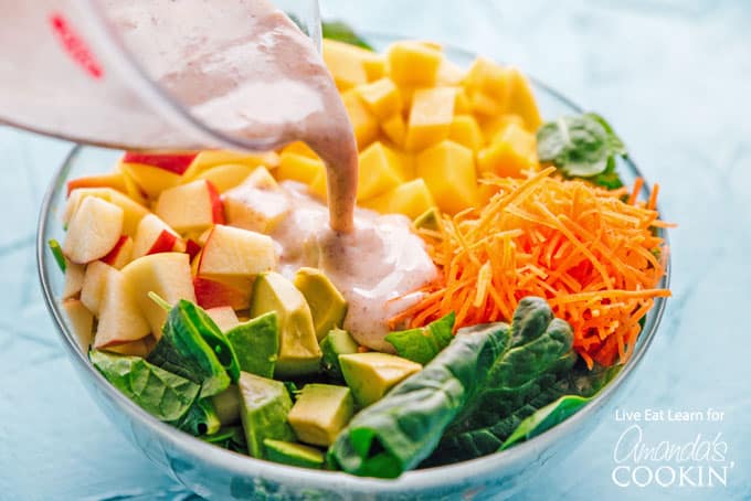 pouring dressing on spinach salad